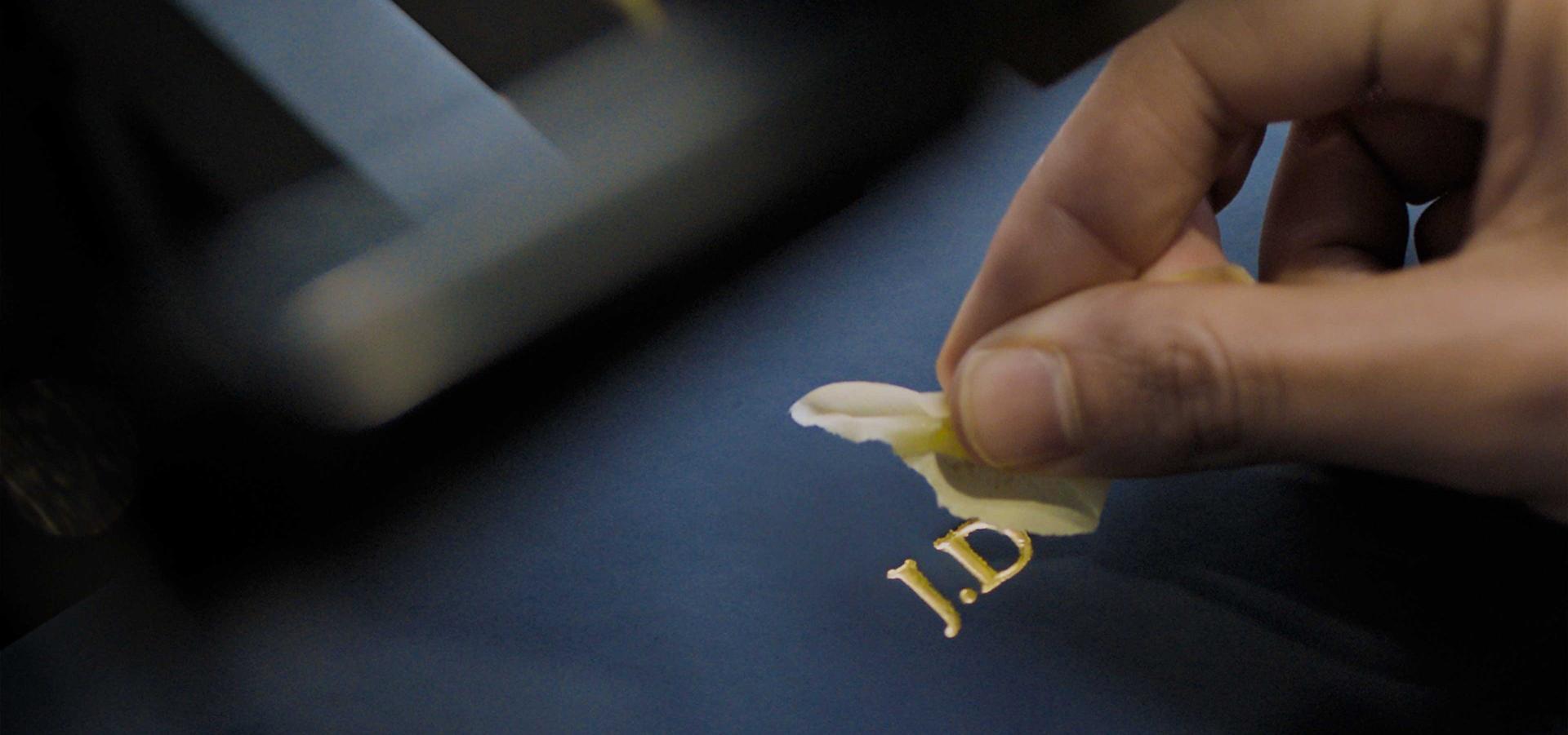 A close-up of a hand applying gold deboss to a Prussian blue Presentation case.