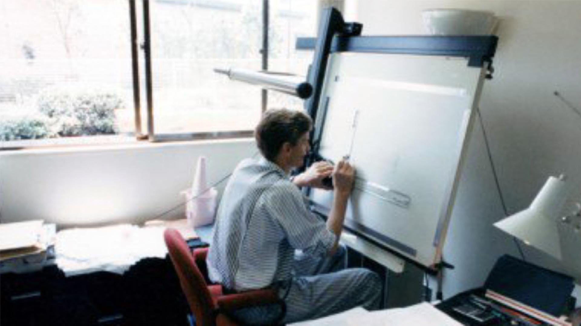 James Dyson seated in front of a technical drawing board