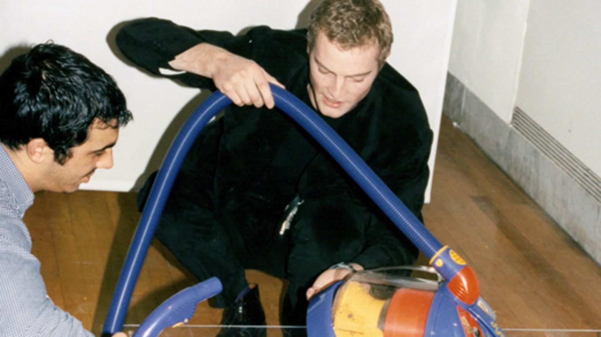 Jake Dyson crouched demonstrating a colourful DC02 vacuum at the Design Museum