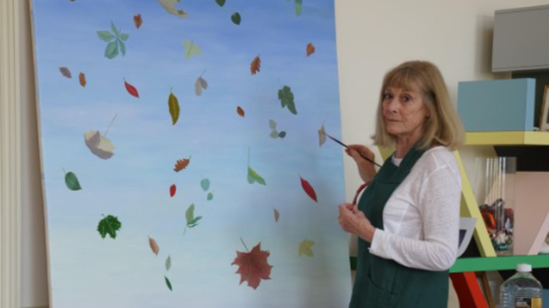 Deirdre Dyson painting falling leaves on a large canvas