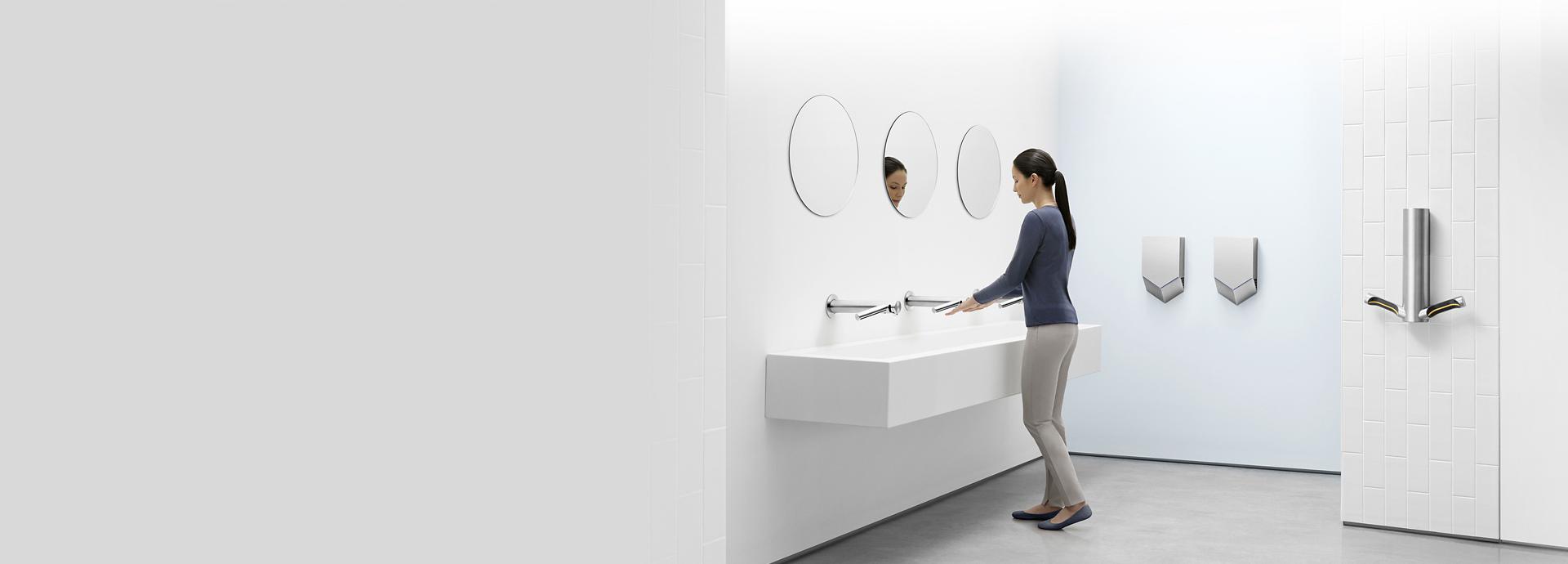 Woman in a bathroom surrounded by different Dyson Airblade machines