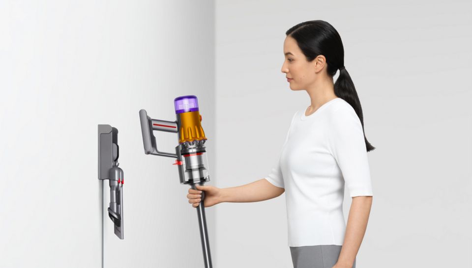 Woman placing the Dyson V15 Detect vacuum on the wall dock