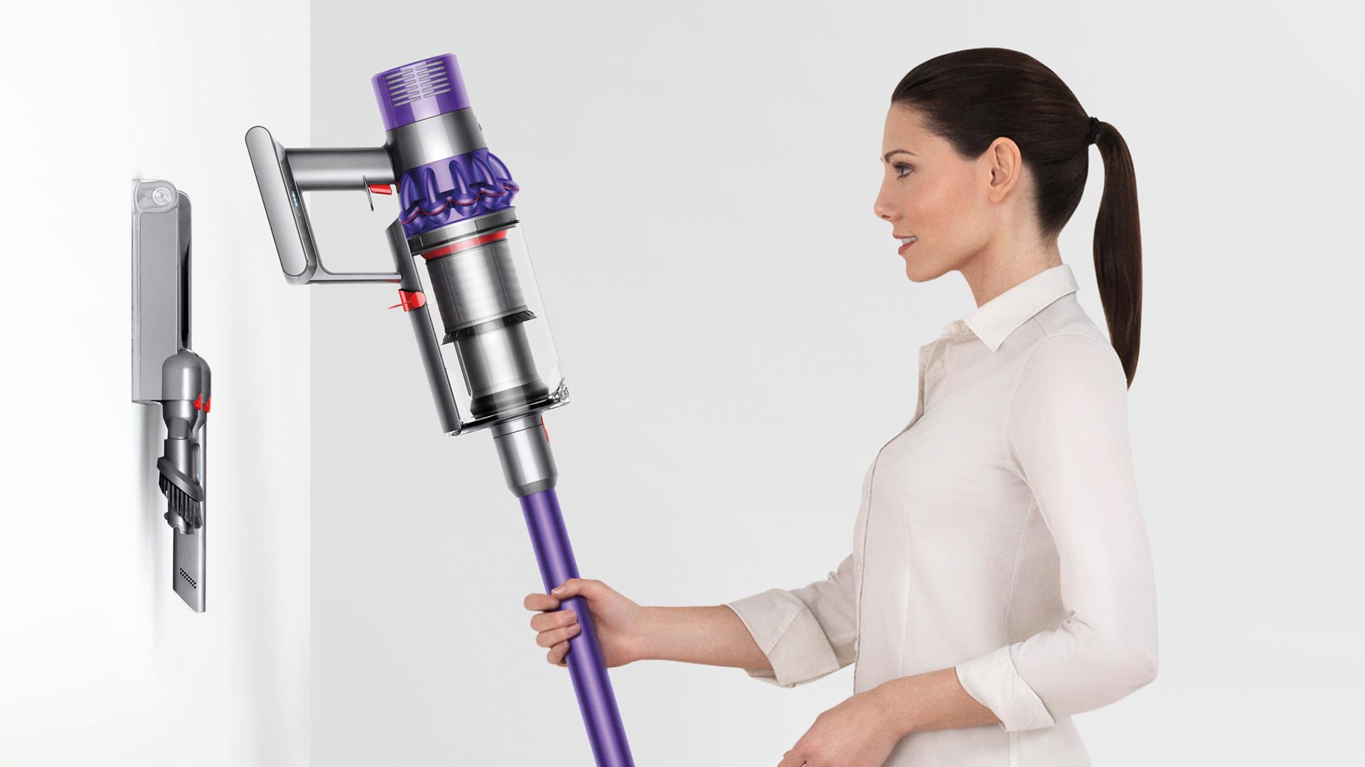 Woman placing the Dyson Cyclone V10 neatly inot docking station