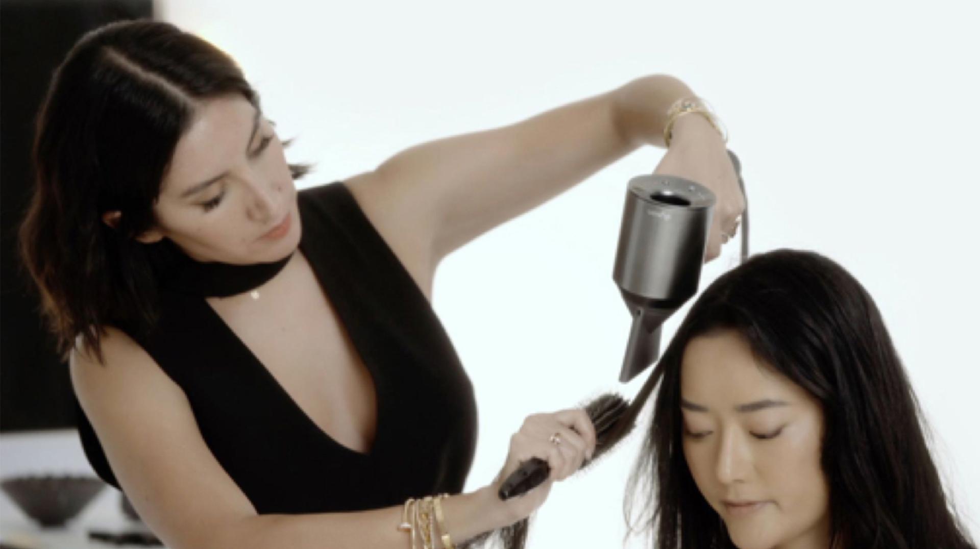 Professional hair stylist using the Dyson Supersonic hair dryer on a customer